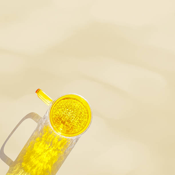 istock Yellow colored glass cup with beautiful sunlight shadow and caustics effect on beige background. Top view mug for tea and coffee, minimal aesthetic top view summer still life, copyspace 2249906176