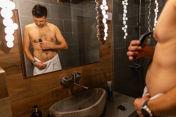 istock Man In Bathroom Reflecting On Grooming Routine While Shaving With Electric Razor 2249907859