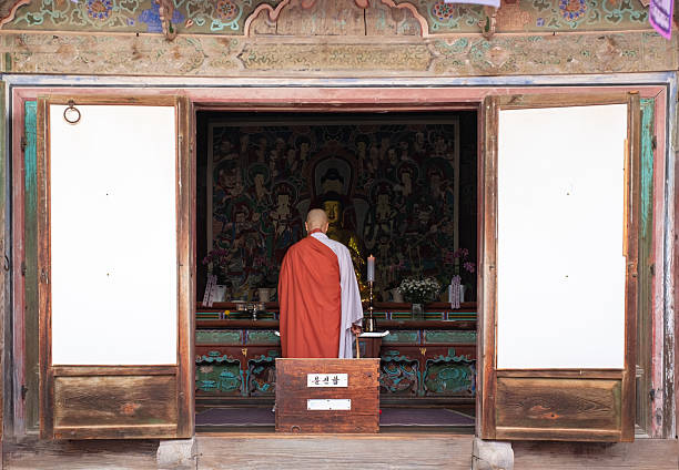 Gyeongju, South Korea November 13, 2025. Monk dressed in traditional robes engrossed in prayer within the walls of an ancient Buddhist temple, evoking a peaceful and sacred ambiance that mirrors deep devotion