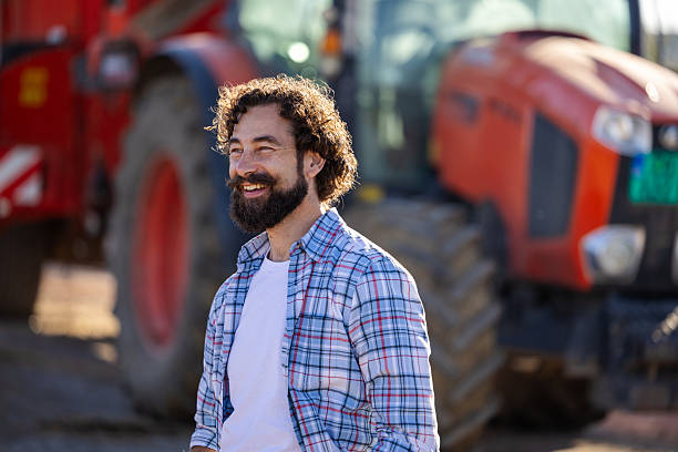 istock Farmer standing in front of tractor on farm 2249910822