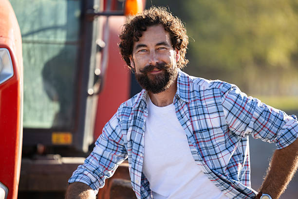 Crop harvesting. Agriculture equipment. Farmer with harvesting machinery. Mature man at tractor. Tractor driver. Agriculture and field work. Farmer in field with tractor outdoor. Point finger.