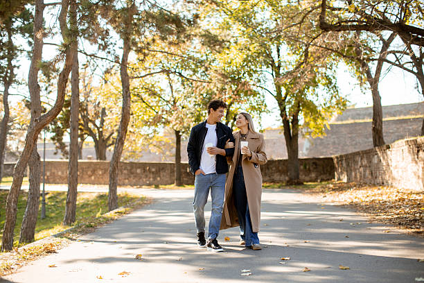 istock Couple enjoys autumn walk in park under colorful trees while sipping coffee 2249910911