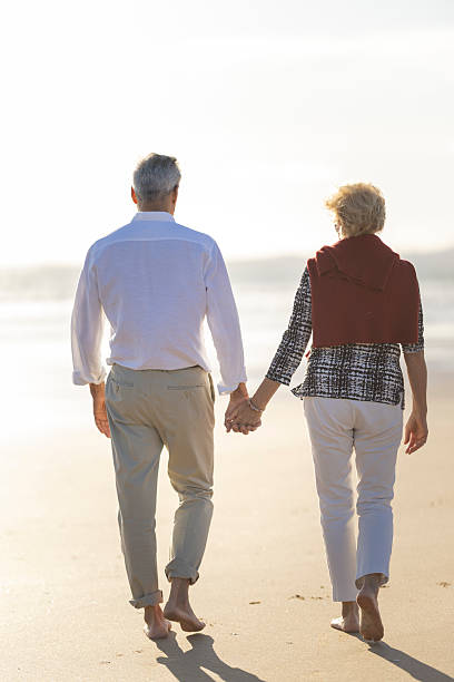 istock Senior couple walking barefoot holding hands on beach 2249910945
