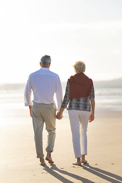 istock Senior couple walking on beach holding hands at sunset 2249911234