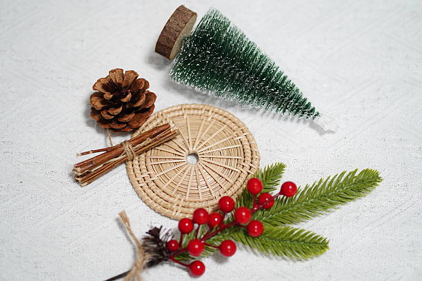istock Festive Holiday Decorations with Miniature Christmas Tree, Pine Cone, Rattan Mat, Red Berries, and Green Foliage on Elegant Background 2249911500