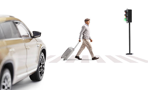 istock Elderly gentleman walking in front of a car and pulling a suitcase 2249911693