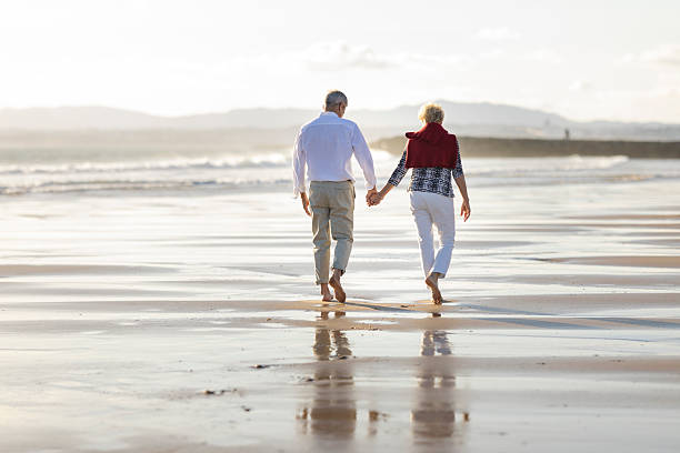 istock Senior couple walking hand in hand on beach 2249914116