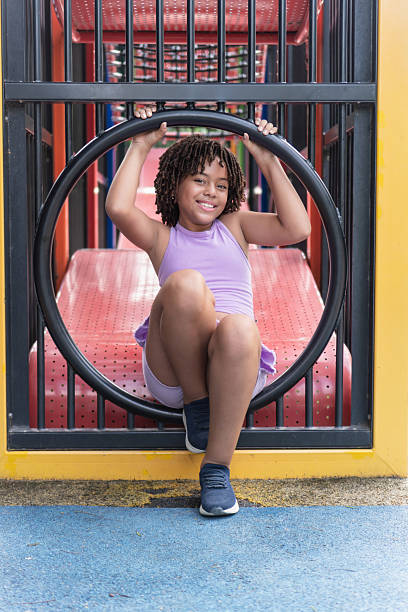 Small child with long red hair against the background of a blue sky in warm clothes on the playground