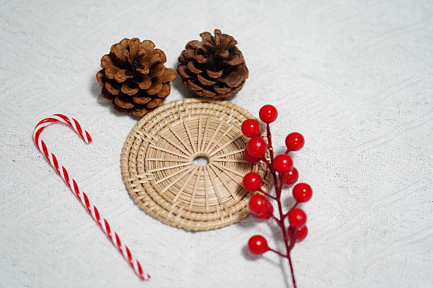istock Festive Decoration Elements with Pinecones, Red Berries, Candy Cane, and Circular Natural Mat on White Background for Holiday Themes 2249915144