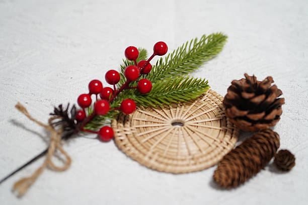 istock Festive arrangement featuring red berries, greenery, pinecones, and a woven mat on a textured white surface for holiday decoration and celebration 2249915177