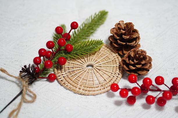 istock Festive natural decorations featuring pinecones, red berries, and green foliage arranged on a woven mat for holiday season photography and design projects 2249915182