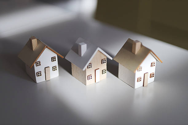 istock Three miniature wooden houses on white surface with soft lighting 2249915374