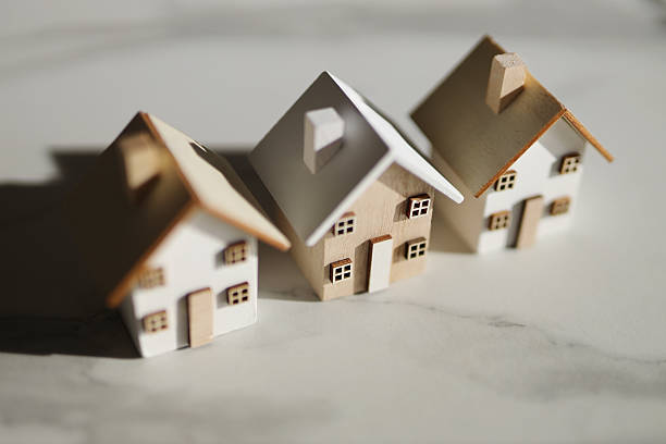 istock Miniature wooden houses on marble surface with sunlight shadows 2249915411