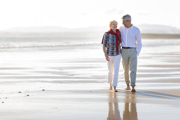 istock Senior couple walking arm in arm on beach 2249915443