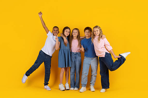 istock Cheerful group of preteen pupils making different gestures on yellow studio background 2249916162
