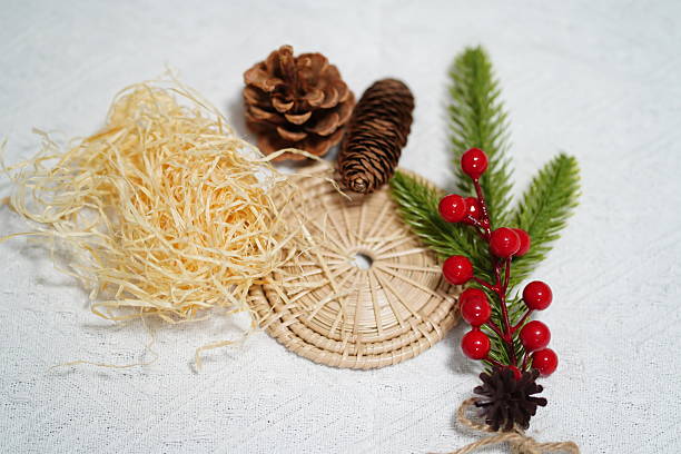 istock Natural Christmas Decoration Elements Including Pine Cones, Berries, Faux Greenery, Straw, and Woven Mat on a Light Background 2249916293