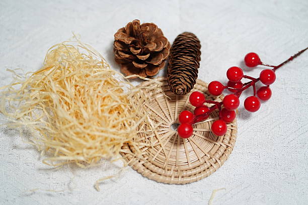 istock Natural elements featuring pine cones, red berries, wicker basket, and straw on textured background for decorative and artistic purposes 2249916330