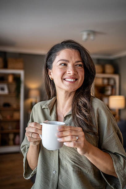 istock Woman smiling holding coffee mug relaxing at home 2249917069