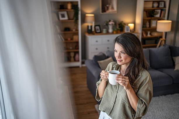 istock Woman drinking coffee quietly looking out window at home 2249917122