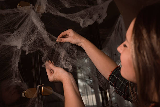 istock Woman decorating home for Halloween with fake spider web 2249917535