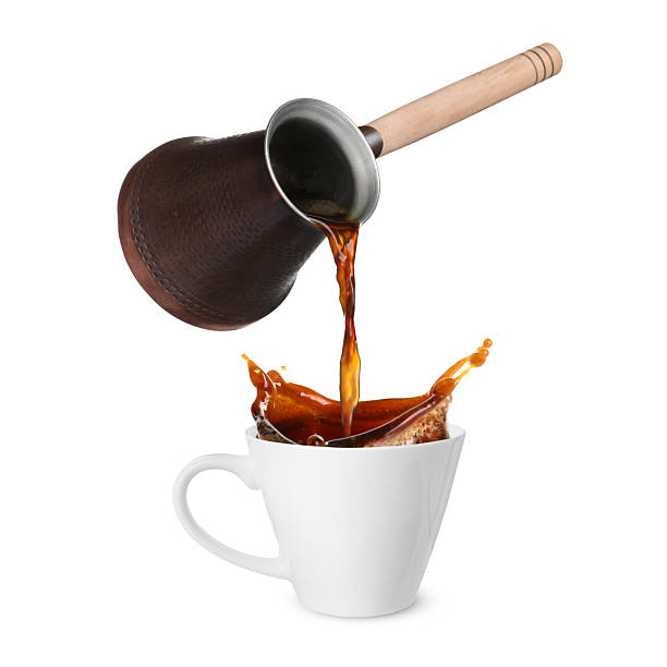 istock Pouring freshly brewed aromatic coffee from turkish pot into cup. Objects in air on white background 2249919578
