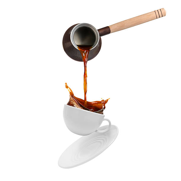 istock Pouring freshly brewed aromatic coffee from turkish pot into cup. Objects in air on white background 2249919759