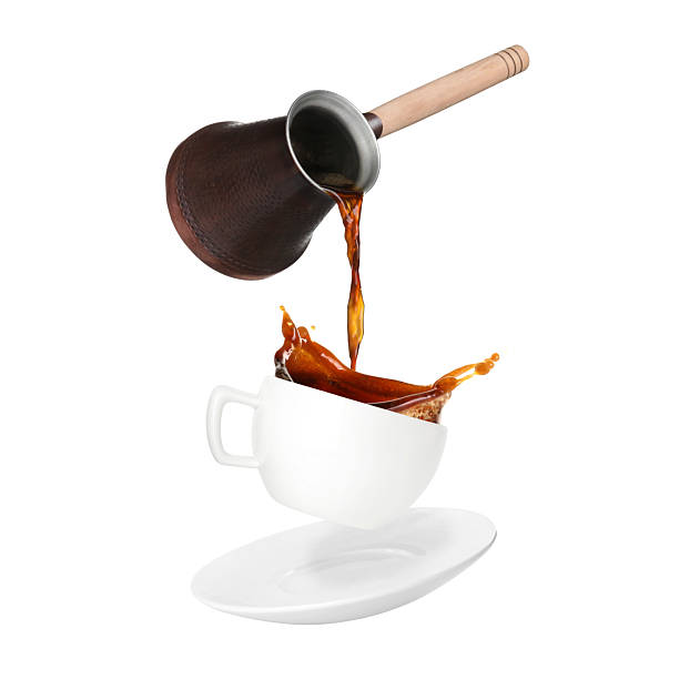 istock Pouring freshly brewed aromatic coffee from turkish pot into cup. Objects in air on white background 2249919777