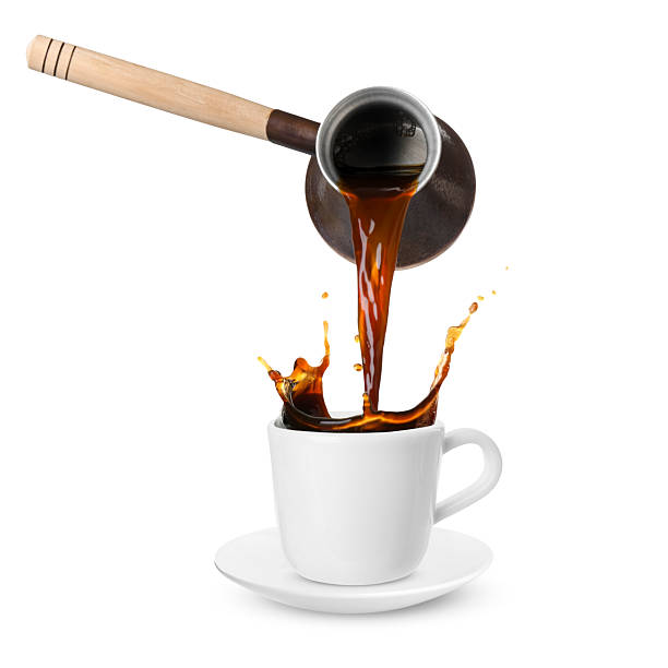 istock Pouring freshly brewed aromatic coffee from turkish pot into cup. Objects in air on white background 2249919787