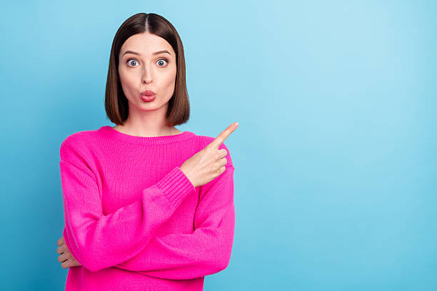 istock Photo of charming impressed young lady wear pink pullover lips pouted pointing finger empty space isolated blue color background 2249923642
