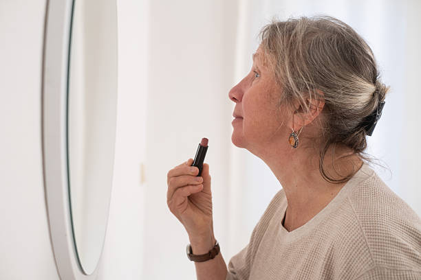istock Attractive senior woman applying lipstick on her lips 2249923899