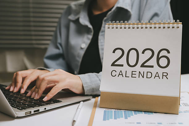 istock 2026 calendar on desk with person typing on laptop, office workspace with pen and documents, planning and organization concept with business charts 2249938886