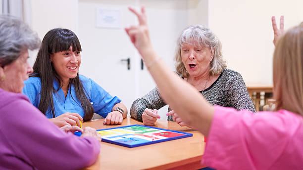 istock Seniors and caregiver playing board game in nursing home 2249941701