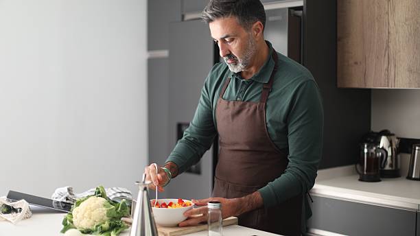istock Man preparing fresh healthy salad in modern kitchen 2249942554