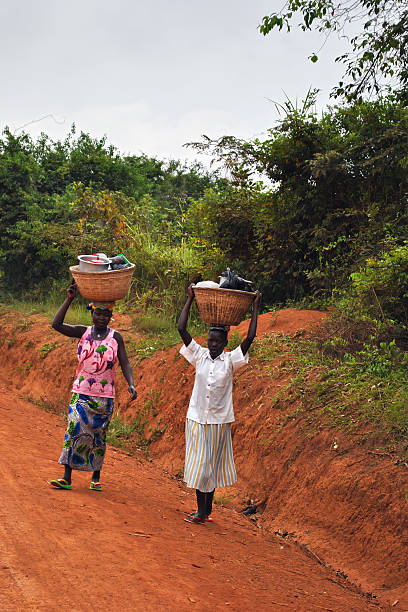 Uganda, Africa - Aug 27, 2010: African women going along a country road carrying a load on they heads
