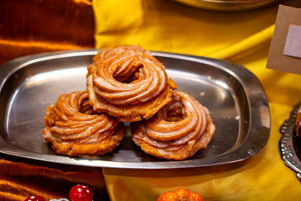 istock Traditional glazed cruller donuts on a metal tray, freshly displayed pastries arranged attractively at a lively market stand 2249958038