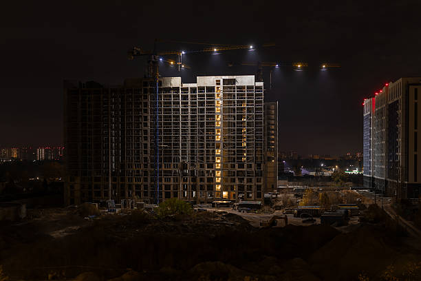 Striking nighttime view of a high-rise construction site, emphasizing the massive building frame and cranes for themes of business, urban development, and industry.