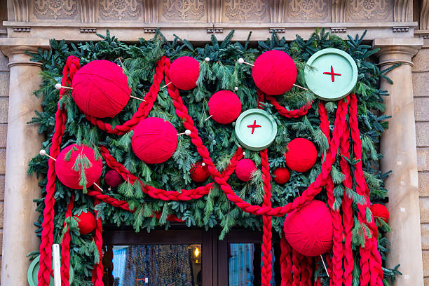 istock Christmas decoration with red yarn balls, braided ropes and green branches displayed on a stone building facade during winter 2249959352