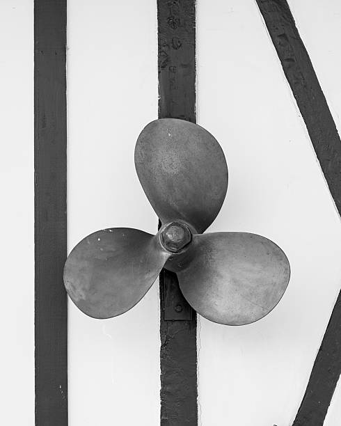 A small ship propeller hangs on a wall in Trouville-sur-Mer France captured in black and white creating a nautical atmosphere.