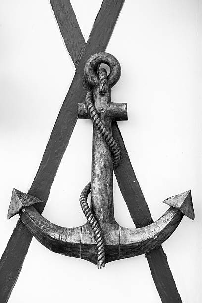 An anchor hangs on a wall in Trouville-sur-Mer France captured in black and white creating a strong maritime atmosphere.