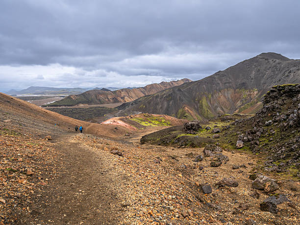 istock A rocky, desolate trail descends into a valley of colorful rhyolite mountains under a brooding gray sky. 2249966118