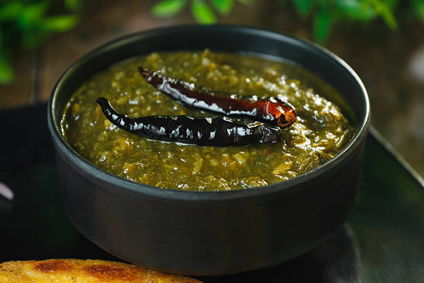 Traditional Punjabi sarson ka saag served with makki di roti, green chilies, onion slices, and fresh garnish.