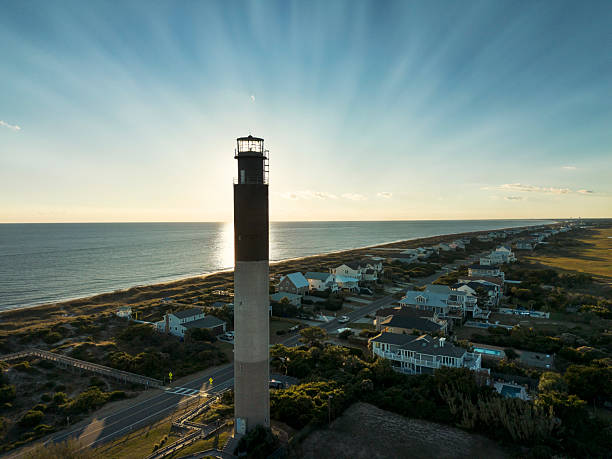 istock Sunset behind the lighthouse with beachfront houses on Oak Island NC 2249973319