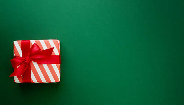 istock Red gift box with red bow on festive green background with copy space for text, Christmas card design. Design element. 2249973511