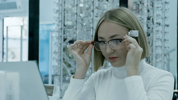 istock woman tries on clear-framed glasses, smiling while looking at her reflection 2249979555