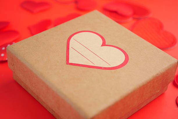 A decorative box featuring a heart design sits among red heart cutouts.