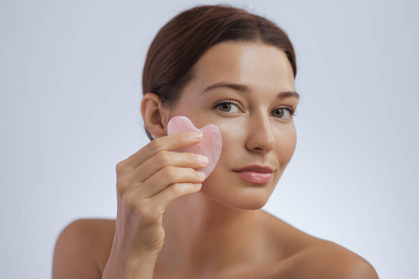 istock Woman Massaging Face with Rose Quartz Gua Sha Tool for Skincare Routine 2249980409