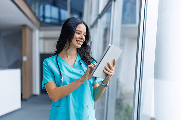 istock Smiling female doctor using digital tablet in hospital corridor 2249981233