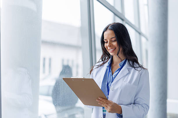 istock Female doctor smiling while holding medical clipboard 2249981353