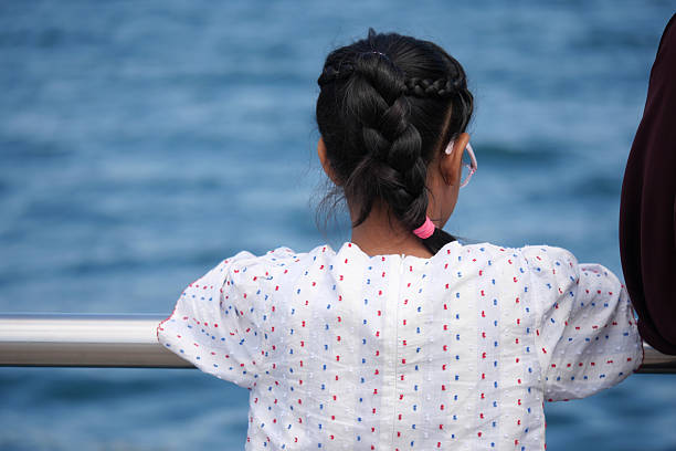 istock Child gazes over water while relaxing at the seaside 2249982346