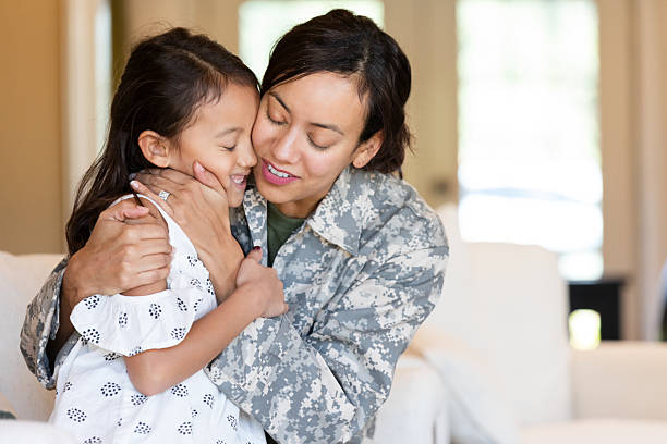 Mother in military uniform embraces her daughter with affection and joy.